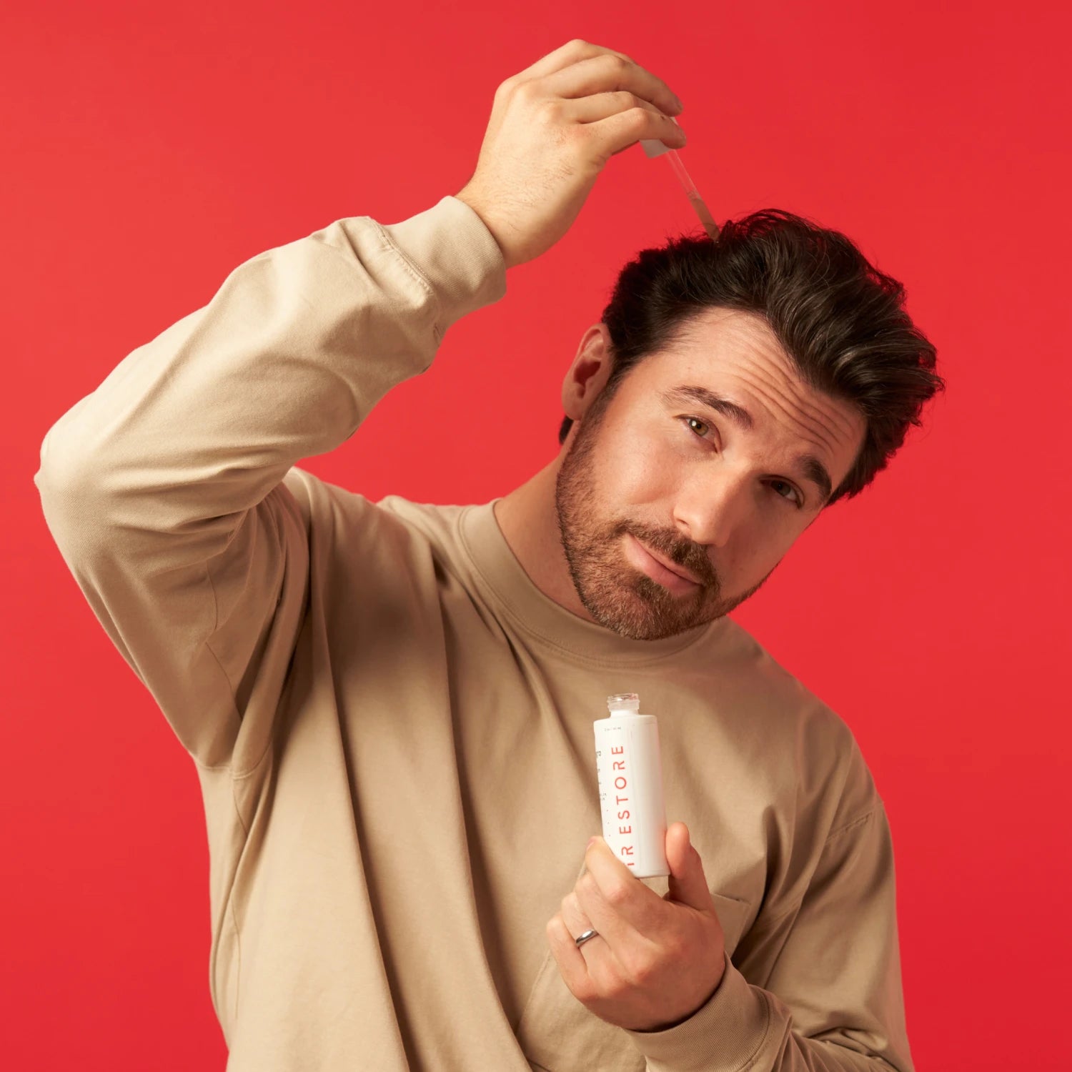 Image of a man holding the Growth Activator Serum and applying the serum directly on his hair.