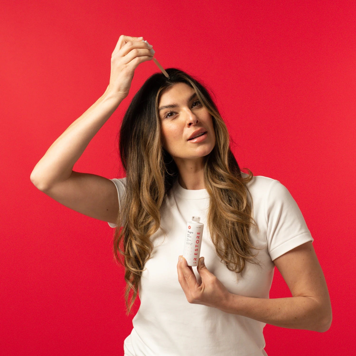 Image of a woman holding the Growth Activator Serum and applying the serum directly on her hair.