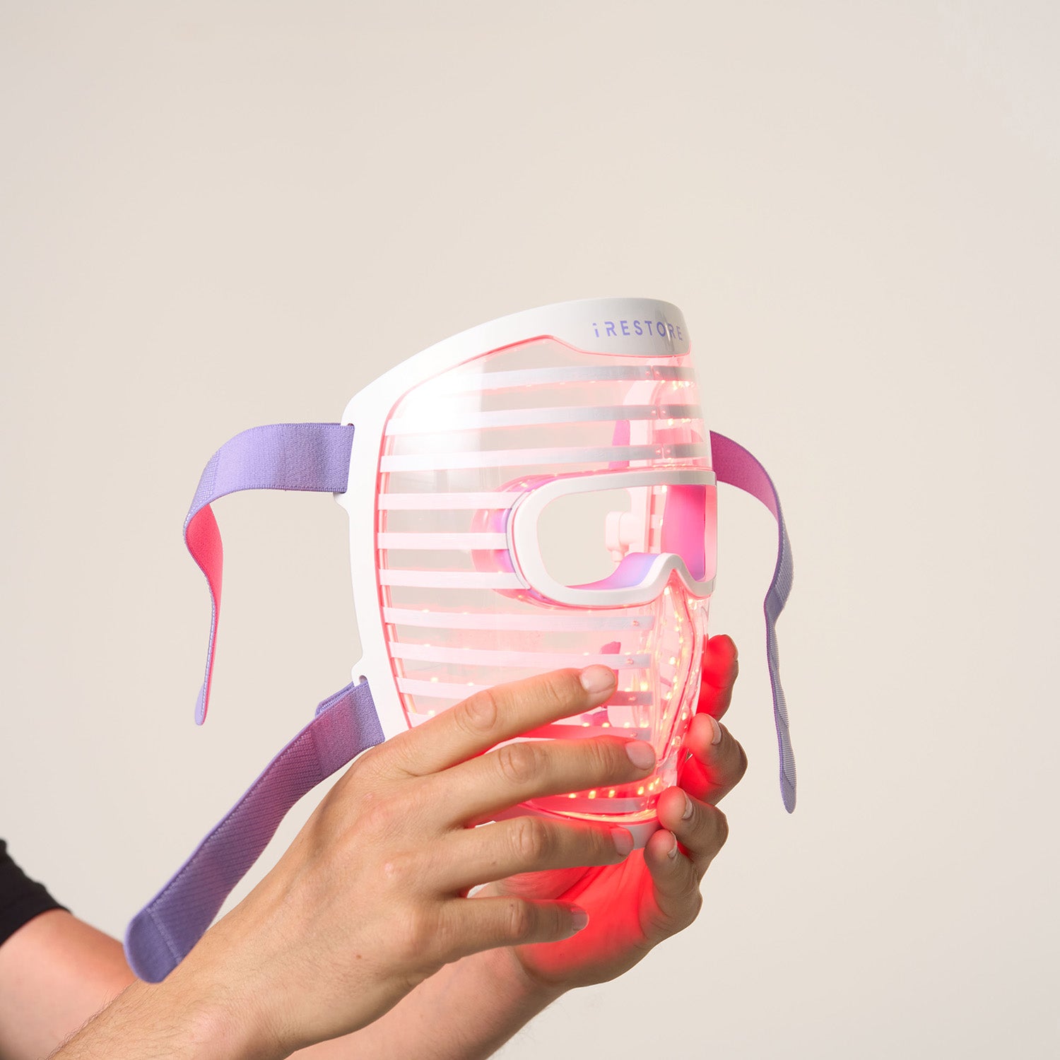 Close up shot of hands holding the LED face mask with red light turned on