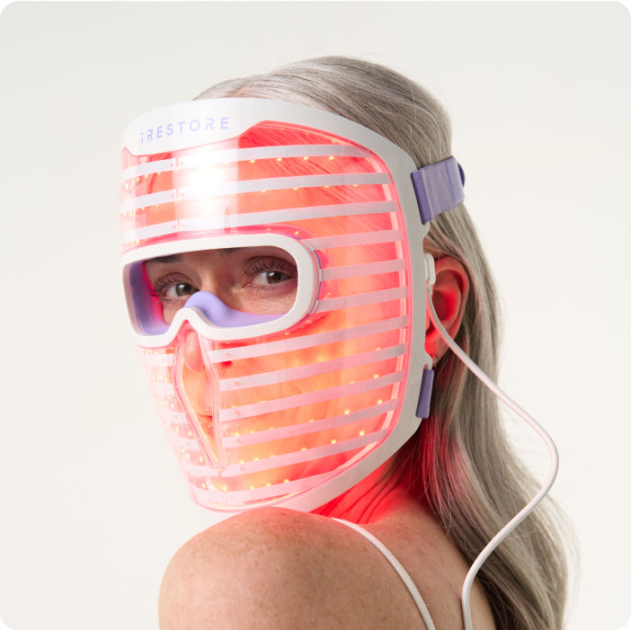 Woman wearing Illumina Face Mask device with red light turned on.